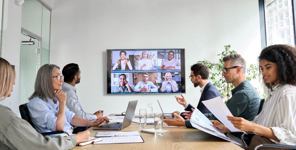 Team collaborating via video conferencing in a hybrid workplace.