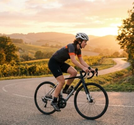Cyclist maintaining an ergonomic posture on a scenic paved road at sunset.